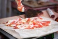 Close-up of thin slices of Italian ham, prosciutto crudo weight on scale, grocery store. Real scene in supermarket Royalty Free Stock Photo