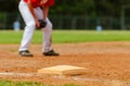 Close up of the third baseball base and a foul line with grass outfield in the background. Baseball diamond Royalty Free Stock Photo