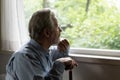 Close up thoughtful mature man holding cane, looking out window Royalty Free Stock Photo