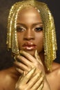 Close-up of thoughtful young black woman looking away with hand under the chin, golden accessories, make-up Royalty Free Stock Photo