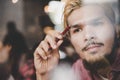 Close up of thoughtful young hipster man while working in cafe.