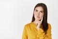 Close-up of thoughtful young woman searching solution, looking up and thinking with focused face, standing over white Royalty Free Stock Photo