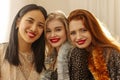Close-up of three beautiful young interracial ladies with red lipstick looking at camera indoors. Royalty Free Stock Photo
