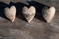 Close-up of three birch wood hearts lying next to each other. You can see the bark on every heart. The hearts are on a tree trunk