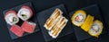 Close-up, on three black containers, there are assorted Japanese rolls, tuna, with soft cheese and teriyaki sauce and baked