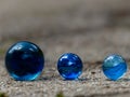 Close up of three blue glass marbles in a row with blurred background space to place text Royalty Free Stock Photo