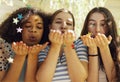 Close up of three cute happy teenage girls of different nationalities blowing star shaped confetti from their hands