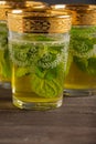 Close-up of three decorated mint tea glasses, selective focus, on wooden table, dark background Royalty Free Stock Photo