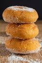Close-up of three donuts in stack on wooden board with sugar and black background Royalty Free Stock Photo