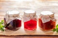 Close-up three glass jars with homemade  jam are standing in row on wooden background. Royalty Free Stock Photo