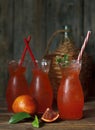 Close-up of three glasses with fresh home-made juice of a bloody orange with ice and mint on a vintage wooden background.