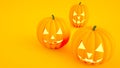 Close-up of three glowing Halloween pumpkins with smile, on orange background