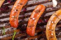 Close up of three grilling sausages on barbecue grill with some species. BBQ in the garden. Bavarian sausages Royalty Free Stock Photo