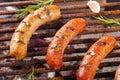 Close up of three grilling sausages on barbecue grill with some species. BBQ in the garden. Bavarian sausages Royalty Free Stock Photo