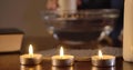 Close-up of three lighting candles standing on the table, cards lying behind. Female Caucasian hand moving big candle