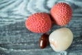 Three lychee fruits and seed on wooden background