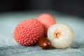 Three lychee fruits and seed on wooden background