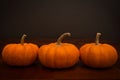 Three mini pumpkin with dark background on wooden table Royalty Free Stock Photo