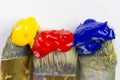 Macro three paint brushes with red, yellow and blue paint on a white background. Place for text, for banner, for site.