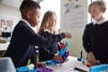 Close up of three primary school children working together with toy construction blocks in a classroom, side view