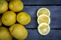 Close up of Three slices of lemon arranged with a group of lemons sitting on a wood table