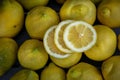 Close up of Three slices of lemon arranged with a group of lemons on a wood table