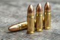 Close-up of three spent bullet shells resting on a wooden table, each casing reflecting light in a unique way Royalty Free Stock Photo