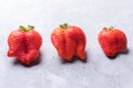 Close-up three ugly red strawberries on concrete background.