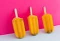 Close up of three yellow ice lollipops upside down on pink background Royalty Free Stock Photo