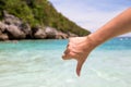 Close-up of thumbs down and dislike gesture in beach sea shore background