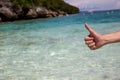 Close-up of thumbs up gesture in beach sea shore background.