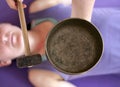 Close up  of a  Tibetan singing bowl held over a womans body who is lying underneath it. Royalty Free Stock Photo