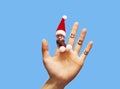 Close-up of a tiny Santa Claus hat on his finger with a smiley face. Crazy New Year. Christmas card