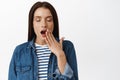 Close up of tired adult woman yawning, close eyes and cover opened mouth during yawn, feel sleepy, early in morning wake