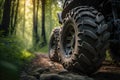 close-up of the tires on atv, with a forest trail visible in the background