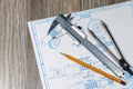 Close up to blue print, pencil, calipers, dividers laying over natural wooden background. Engineering activity and creativity. Royalty Free Stock Photo