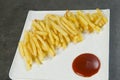 French fries with red ketchup sauce on white plate plate, gray anthracite stone background Royalty Free Stock Photo