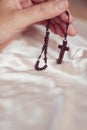 Close up to a hand holding a wooden rosary and crucifix