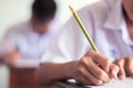 Close up to hand of student is taking exam and writing answer in classroom for education test concept Royalty Free Stock Photo