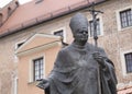 Close up to John Paul II pope monument sculpture with wawel castle facade