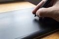 Close up to a male hand holding up a black digital pencil over a black and green drawing tablet in desk and home office background Royalty Free Stock Photo