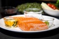 Close up to Salmon Trout steak, Raw fillet of sea fish on white dish with salt, oil, and wasabi cream in studio light on dark Royalty Free Stock Photo