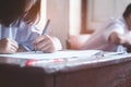 Close-up to student holding pencil and writing final exam in examination room or study in classroom Royalty Free Stock Photo