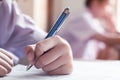 Close-up to student holding pencil and writing final exam in examination room or study in classroom Royalty Free Stock Photo