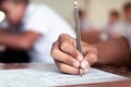 Close-up to student holding pencil and writing final exam in examination room or study in classroom Royalty Free Stock Photo