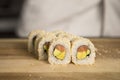 Close up to Sushi roll on wooden table in restaurant kitchen with chef on blurred background. Sushi pieces before serving