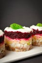 Portion of Layered fish salad Herring under fur coat served in culinary rings.