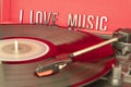 Close up to a turn table needle playing a LP vinyl disc with turn table and I love music lettering over red background Royalty Free Stock Photo