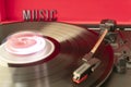 Close up to a turn table needle playing a LP vinyl disc with turn table and MUSIC lettering word over red background Royalty Free Stock Photo