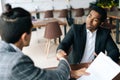 Close-up to two satisfied multiracial businessmen shaking hands over desk after successful negotiations, closing sealing Royalty Free Stock Photo